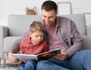 father teaching child how to read a book