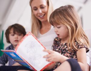 mother teaching children to read a book